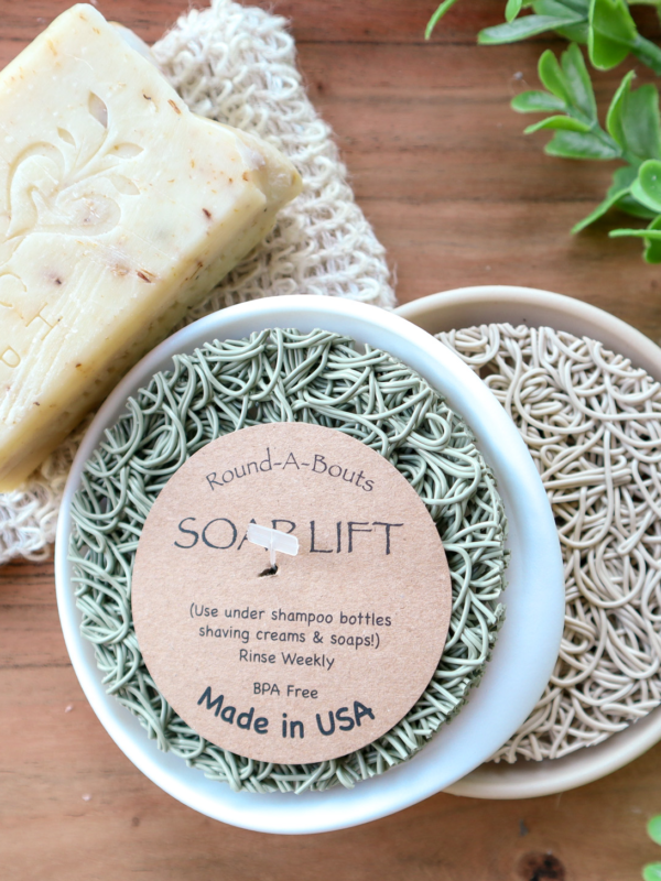 green Round soap lift on white round dish with wood background